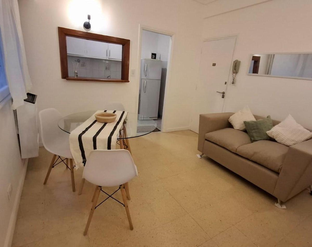 Unidad de dos ambientes interno. Living-comedor con mesa sillas Y sofá.
